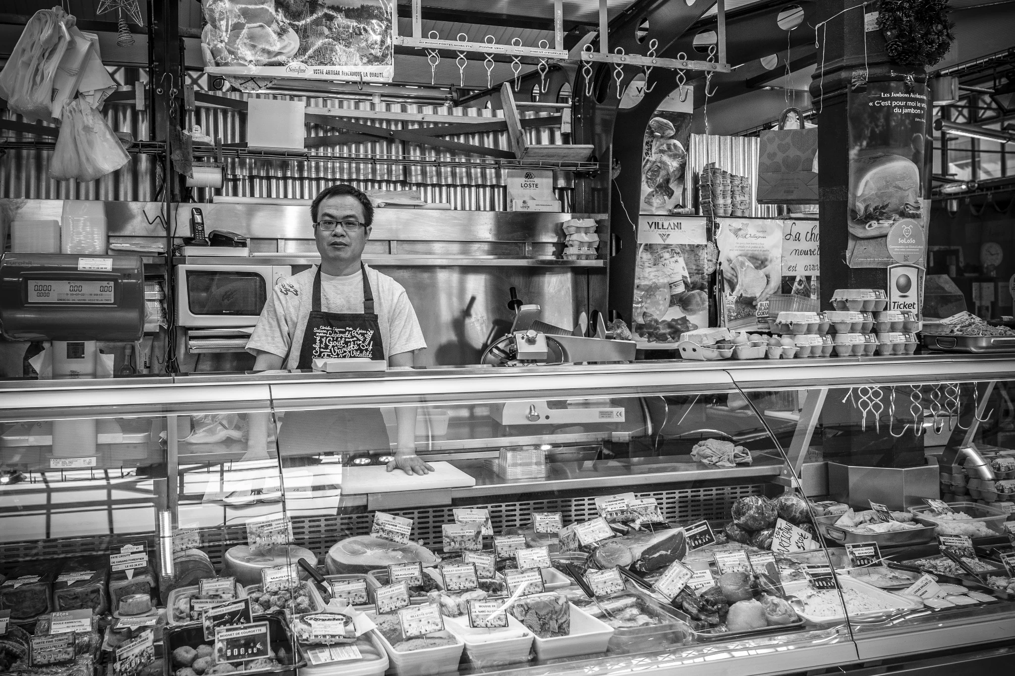 Un commerçant derrière une vitrine de produits frais.