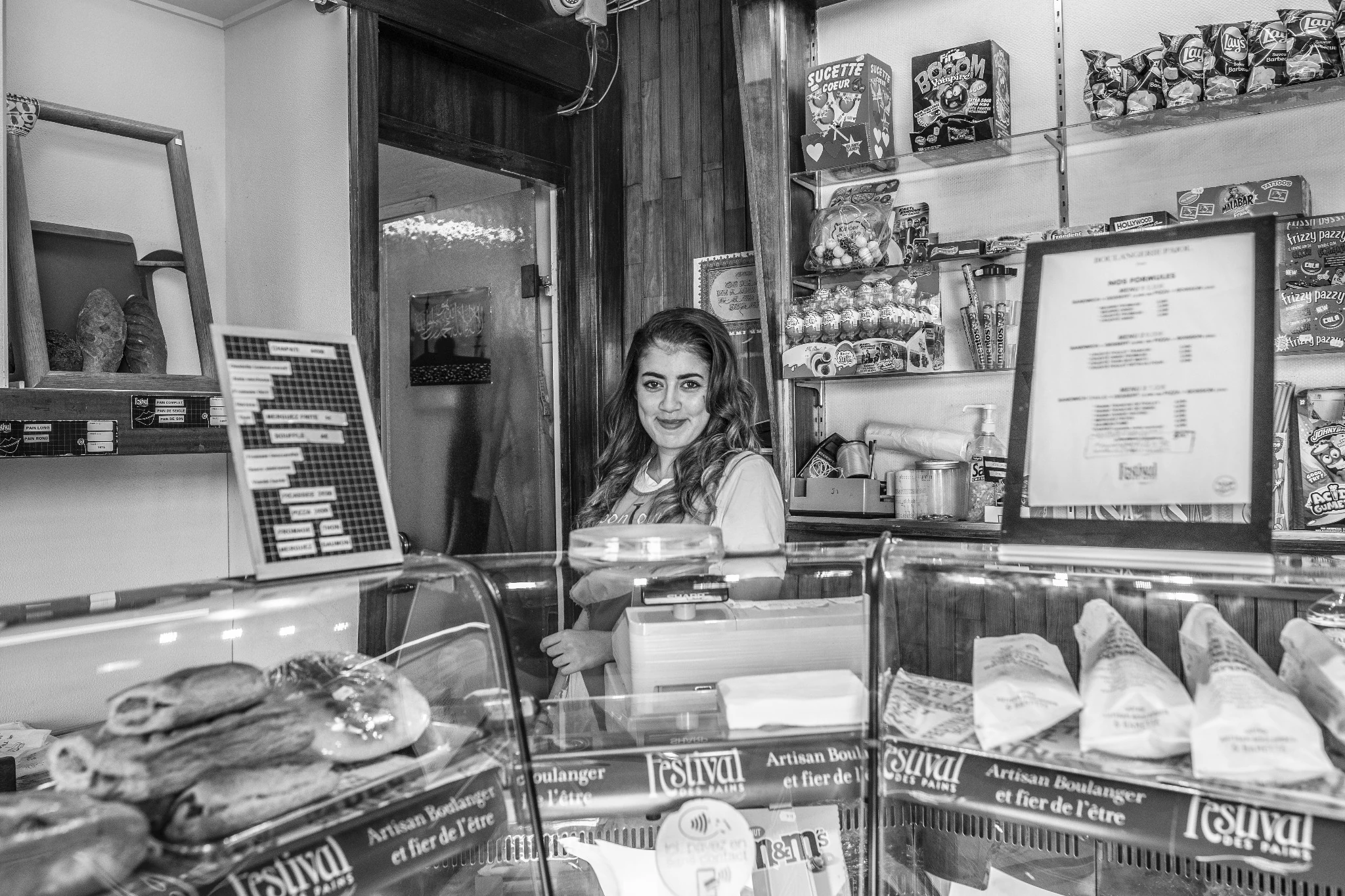 Une commerçante souriante derrière son comptoir.